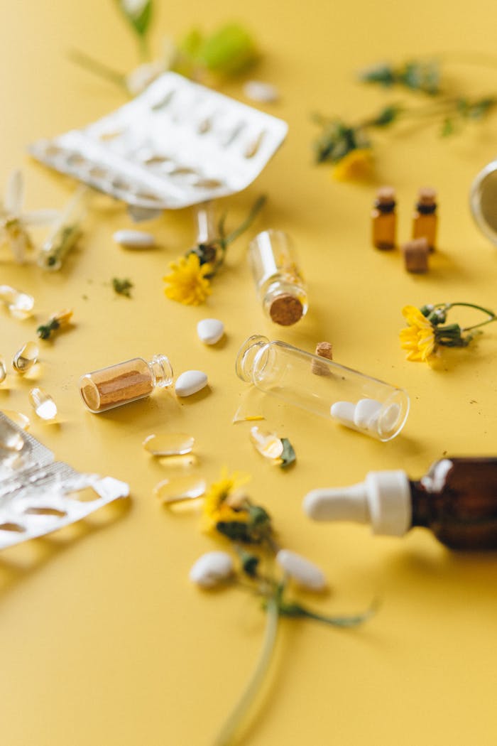 Scattered herbal remedies and pills on a yellow background with flowers.